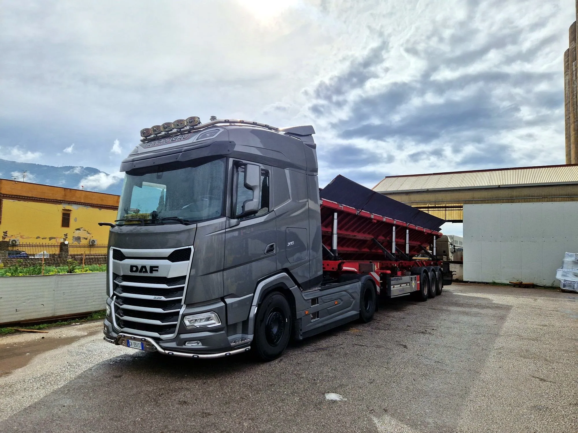 DAF XG grigio agganciato a un semirimorchio rosso a piano inclinato