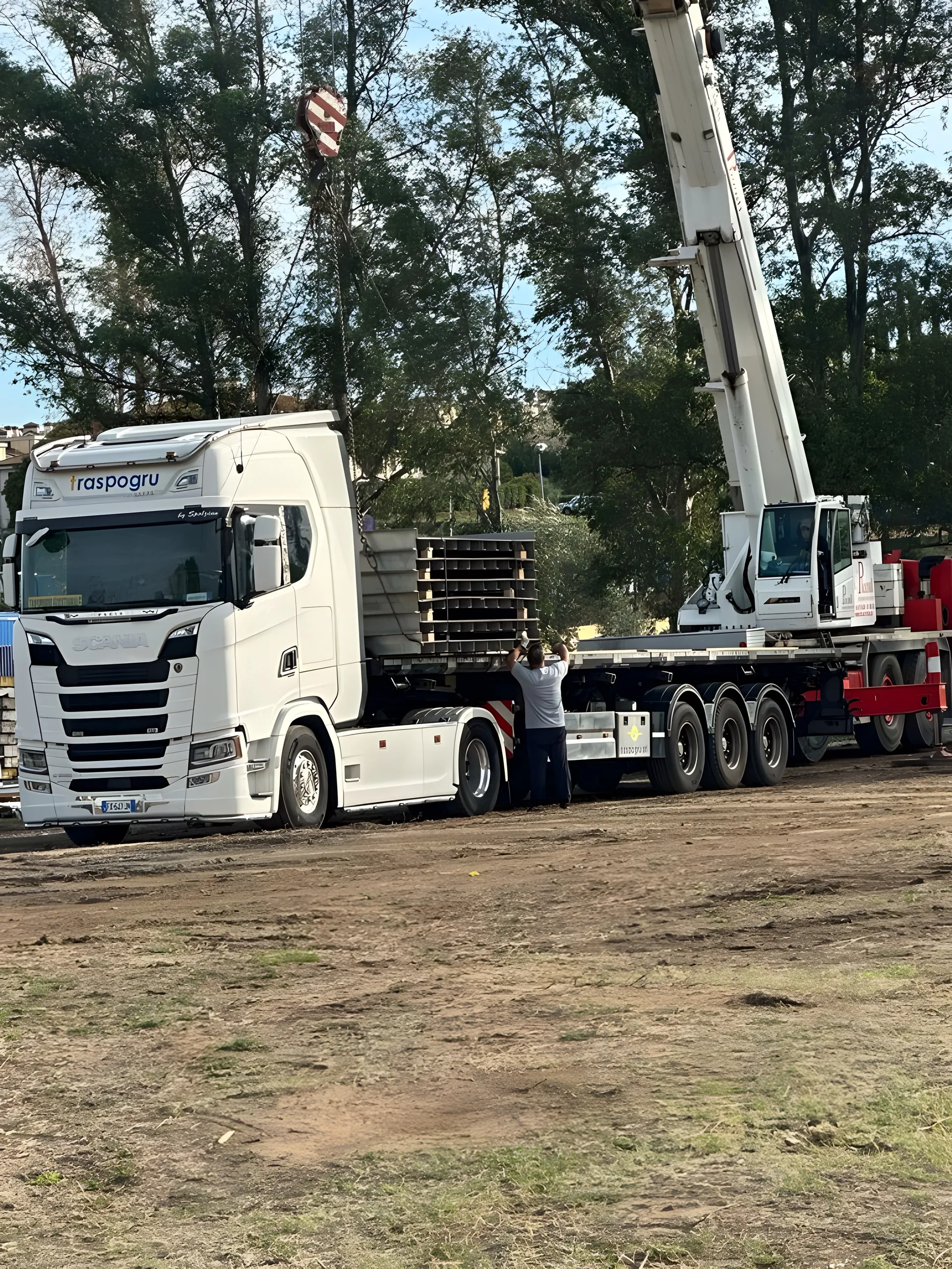 Scania Traspogru con semirimorchio in cantiere mentre un’autogrù scarica il materiale